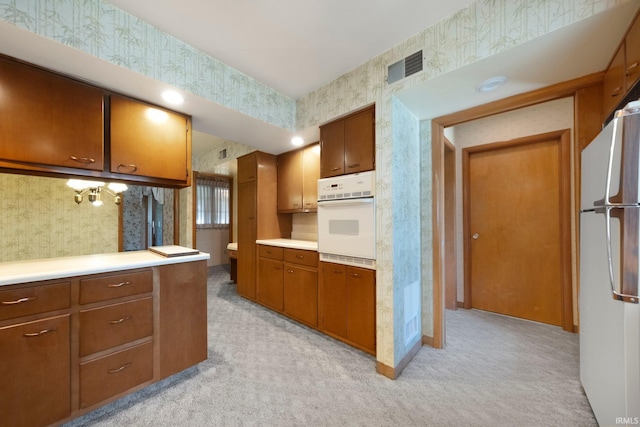 1202 Park Ave, New Haven, IN 46774 - kitchen with white appliances, wallpapered walls, light carpet, light countertops, and brown cabinetry