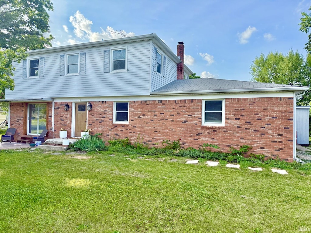 113 W Elm St, Somerset, IN 46984 - view of front of property featuring a chimney, brick siding, a front lawn, and a patio area