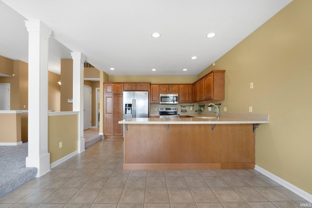 12828 Palazzo Blvd, Fort Wayne, IN 46845 - kitchen with appliances with stainless steel finishes, light countertops, a peninsula, decorative columns, and a kitchen bar