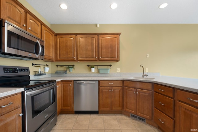 12828 Palazzo Blvd, Fort Wayne, IN 46845 - kitchen featuring appliances with stainless steel finishes, light countertops, brown cabinetry, light tile patterned floors, and recessed lighting