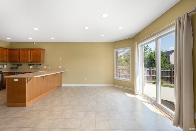12828 Palazzo Blvd, Fort Wayne, IN 46845 - kitchen with light countertops, a peninsula, recessed lighting, a kitchen bar, and brown cabinets