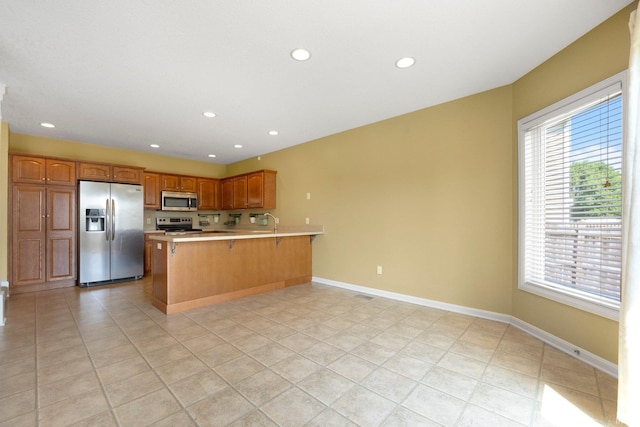 12828 Palazzo Blvd, Fort Wayne, IN 46845 - kitchen featuring appliances with stainless steel finishes, a peninsula, light countertops, recessed lighting, and a breakfast bar area