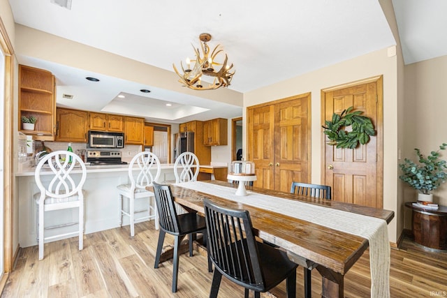 9026 Wallen Ln, Fort Wayne, IN 46825 - dining space featuring a chandelier, a raised ceiling, light wood-style floors, and recessed lighting