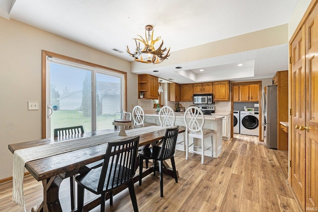 9026 Wallen Ln, Fort Wayne, IN 46825 - dining space with a raised ceiling, washer and dryer, a chandelier, light wood-style flooring, and recessed lighting