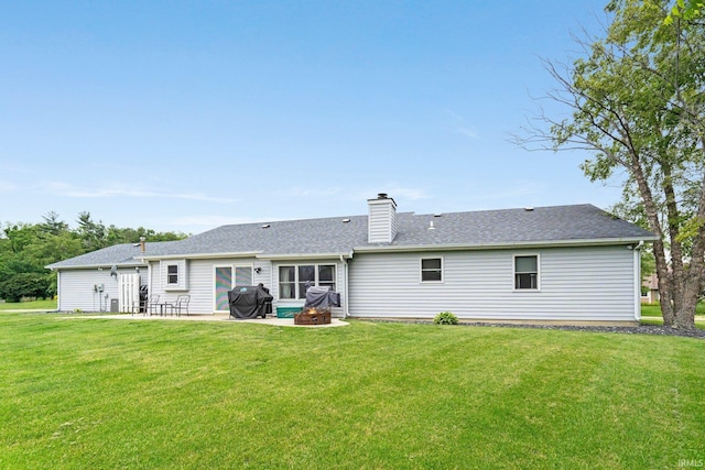9026 Wallen Ln, Fort Wayne, IN 46825 - back of house featuring a patio, a lawn, a chimney, a fire pit, and roof with shingles