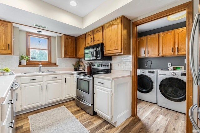9026 Wallen Ln, Fort Wayne, IN 46825 - kitchen with stainless steel appliances, separate washer and dryer, light wood-style floors, and backsplash