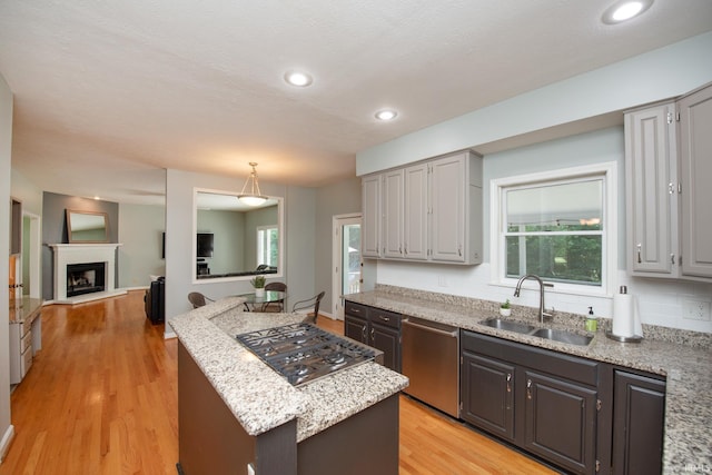 3801 W Capilano Dr, West Lafayette, IN 47906 - kitchen with appliances with stainless steel finishes, light wood-style floors, a kitchen island, a fireplace with raised hearth, and light stone counters