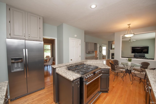 3801 W Capilano Dr, West Lafayette, IN 47906 - kitchen with stainless steel appliances, open floor plan, light wood finished floors, light stone counters, and hanging light fixtures