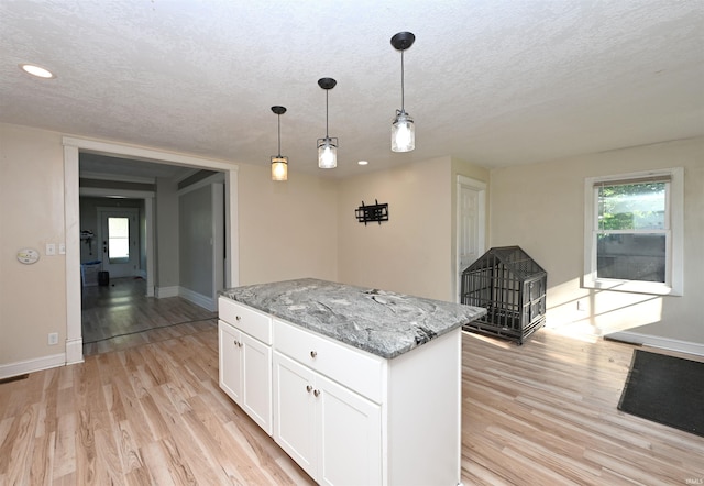 421 S Franklin St, Winamac, IN 46996 - kitchen featuring a textured ceiling, light wood-style floors, a center island, light stone counters, and white cabinetry