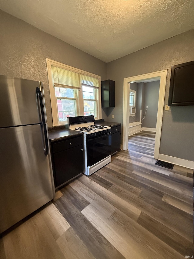 628 Birdsell St, South Bend, IN 46628 - kitchen with freestanding refrigerator, black gas range oven, a textured wall, dark wood finished floors, and a textured ceiling