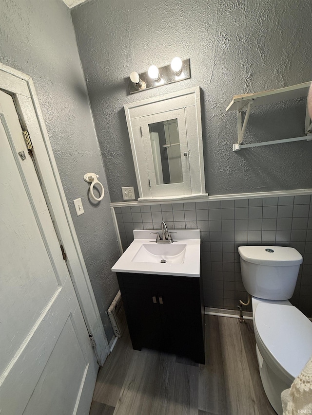 628 Birdsell St, South Bend, IN 46628 - half bathroom featuring wood finished floors, vanity, a textured wall, tile walls, and wainscoting