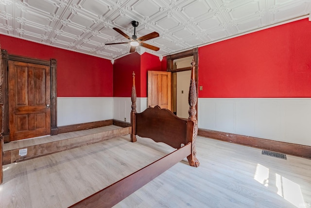 240 Elm St, Wabash, IN 46992 - unfurnished bedroom featuring wood finished floors, an ornate ceiling, a wainscoted wall, and ceiling fan