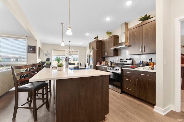 12116 Fazio Dr, Fort Wayne, IN 46818 - kitchen featuring stainless steel appliances, wall chimney range hood, a breakfast bar, light wood-style flooring, and light countertops