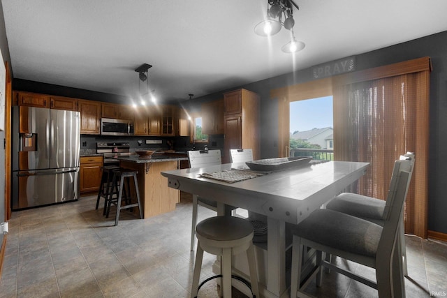 2608 Creeping Phlox Cv, Fort Wayne, IN 46818 - kitchen with stainless steel appliances, dark countertops, a kitchen island, a breakfast bar area, and brown cabinets