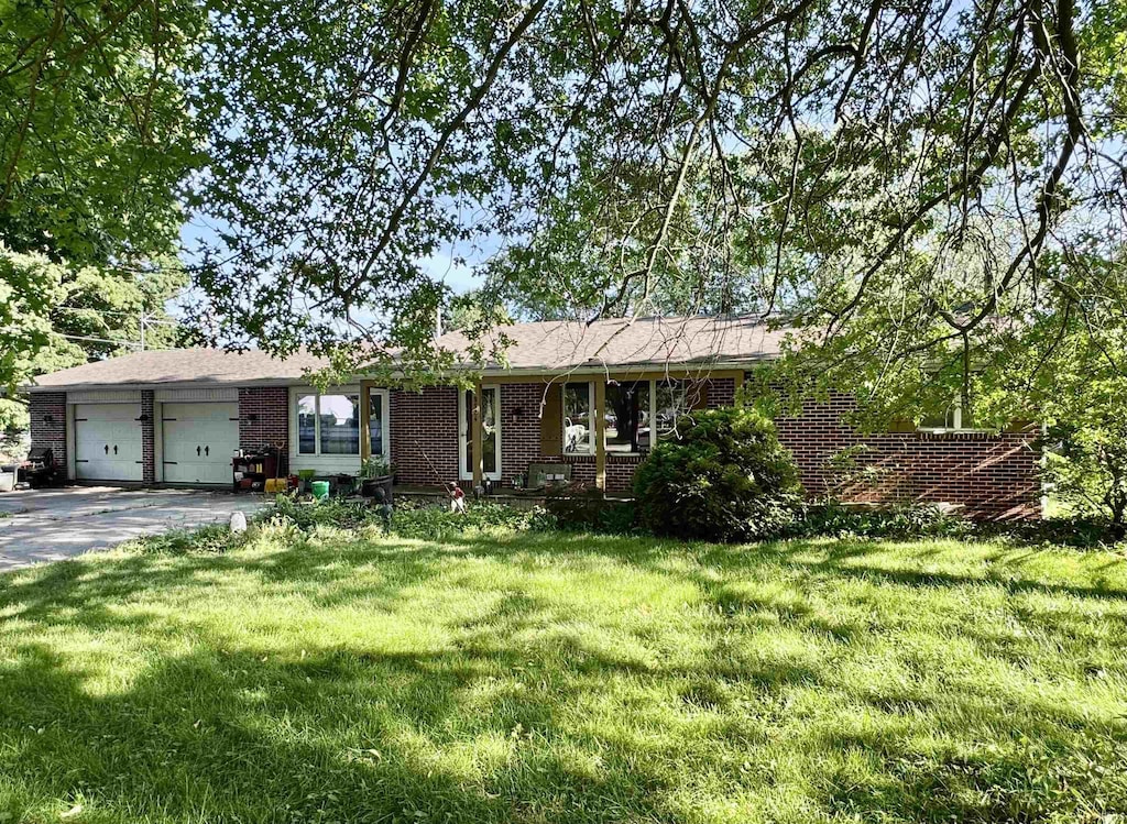 9924 Washington St, Leo, IN 46765 - ranch-style home with brick siding, an attached garage, a front lawn, and driveway