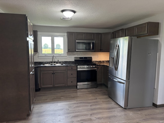 140 W 100 S Rd, Lagrange, IN 46761 - kitchen with stainless steel appliances, dark countertops, backsplash, a textured ceiling, and light wood-style floors