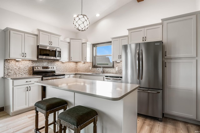 8622 Alamasa Pl, Fort Wayne, IN 46835 - kitchen with appliances with stainless steel finishes, a breakfast bar, tasteful backsplash, light wood-type flooring, and lofted ceiling