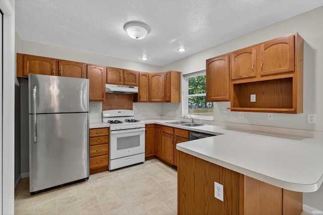 51613 Emmons Rd, South Bend, IN 46637 - kitchen featuring freestanding refrigerator, white range with gas stovetop, under cabinet range hood, a peninsula, and brown cabinets