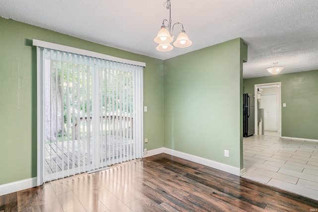 4648 Parkerdale Dr, Fort Wayne, IN 46815 - unfurnished room with wood finished floors, a chandelier, and a textured ceiling