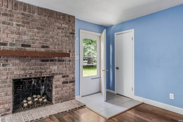 4648 Parkerdale Dr, Fort Wayne, IN 46815 - doorway featuring wood finished floors, a brick fireplace, and a textured ceiling