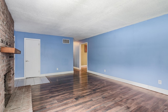 4648 Parkerdale Dr, Fort Wayne, IN 46815 - unfurnished living room featuring a textured ceiling, a brick fireplace, and wood finished floors