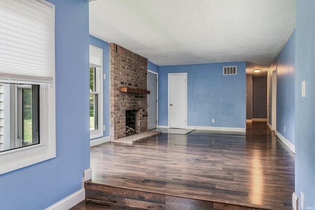 4648 Parkerdale Dr, Fort Wayne, IN 46815 - unfurnished living room with wood finished floors, a brick fireplace, and a textured ceiling