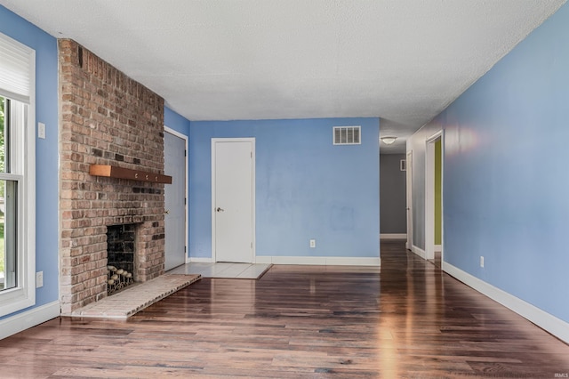 4648 Parkerdale Dr, Fort Wayne, IN 46815 - unfurnished living room with wood finished floors, a brick fireplace, and a textured ceiling