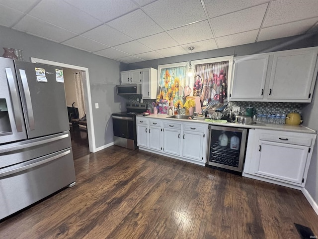 808 19th St, Logansport, IN 46947 - kitchen featuring appliances with stainless steel finishes, beverage cooler, a paneled ceiling, light countertops, and white cabinets