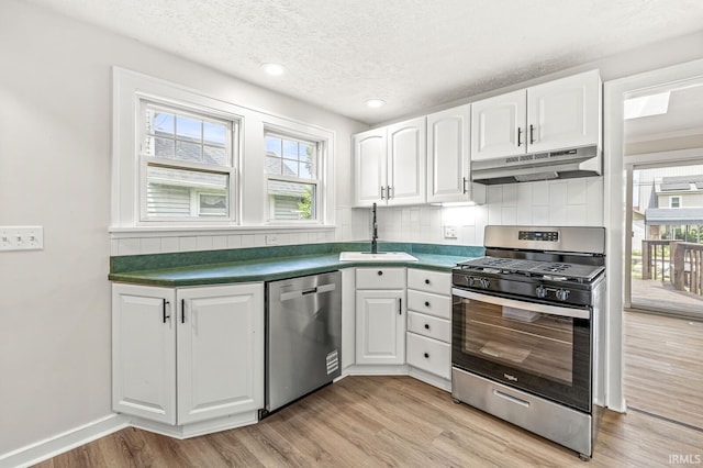 533 Altgeld St, South Bend, IN 46614 - kitchen featuring appliances with stainless steel finishes, under cabinet range hood, backsplash, white cabinets, and light wood finished floors