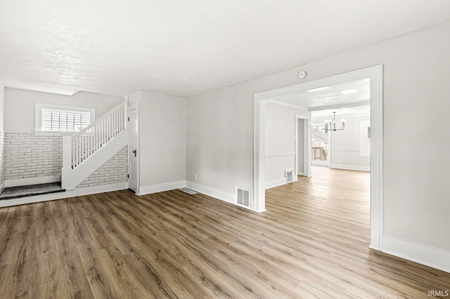 533 Altgeld St, South Bend, IN 46614 - empty room with wood finished floors, a chandelier, stairs, a textured ceiling, and a smoke detector