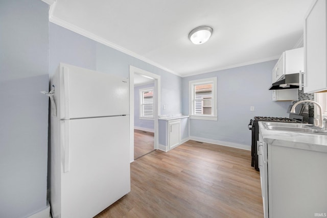 3014 Drexel Ave, Fort Wayne, IN 46806 - kitchen with freestanding refrigerator, ornamental molding, under cabinet range hood, light wood finished floors, and white cabinets