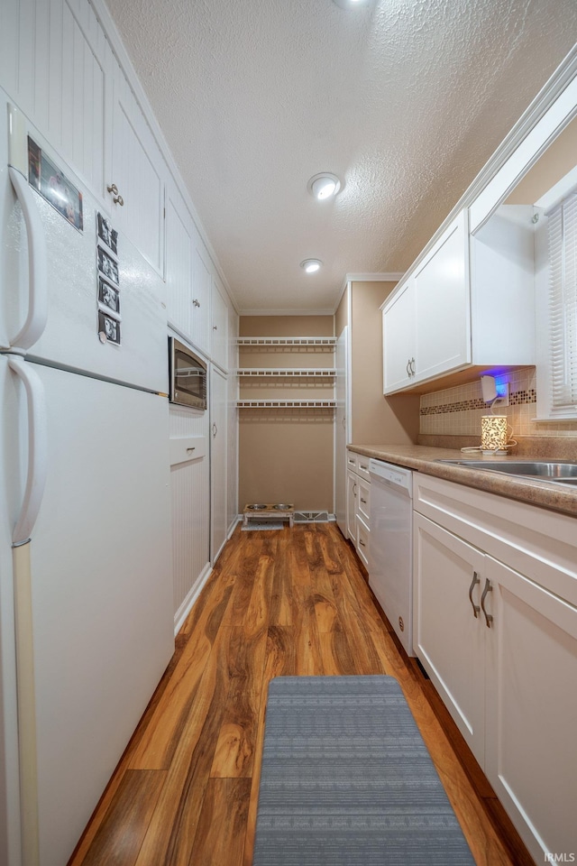 1712 Royal Center Pike, Logansport, IN 46947 - kitchen featuring white appliances, white cabinets, wood finished floors, a textured ceiling, and light countertops