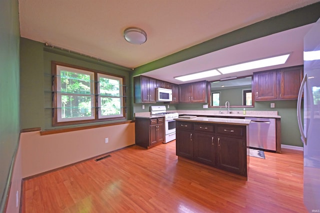 9818 Houndshill Pl, Fort Wayne, IN 46804 - kitchen featuring white appliances, light countertops, light wood-type flooring, dark brown cabinetry, and a center island
