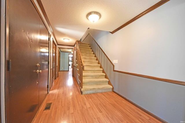 9818 Houndshill Pl, Fort Wayne, IN 46804 - hallway featuring crown molding, a textured ceiling, light wood finished floors, and stairway