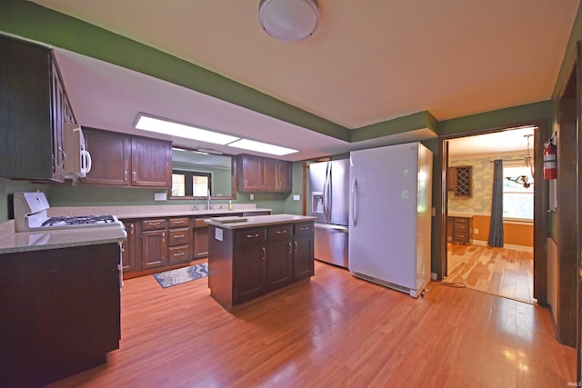 9818 Houndshill Pl, Fort Wayne, IN 46804 - kitchen with white appliances, light wood-style floors, a kitchen island, and plenty of natural light