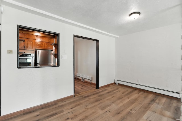58 W Markle Rd, Huntington, IN 46750 - unfurnished room with a baseboard radiator, a baseboard heating unit, light wood-style flooring, and a textured ceiling