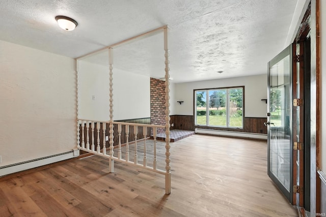 58 W Markle Rd, Huntington, IN 46750 - empty room featuring baseboard heating, a textured ceiling, wood finished floors, and a wainscoted wall
