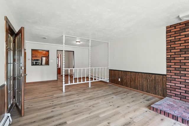 58 W Markle Rd, Huntington, IN 46750 - spare room featuring a baseboard heating unit, light wood-style flooring, wainscoting, and a textured ceiling