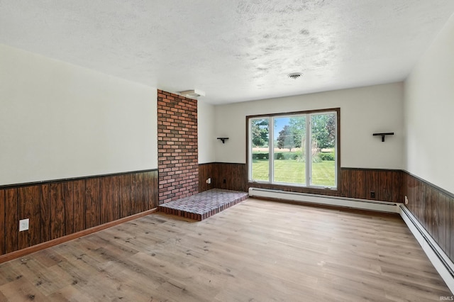 58 W Markle Rd, Huntington, IN 46750 - spare room featuring a wainscoted wall, wood finished floors, wood walls, baseboard heating, and a textured ceiling