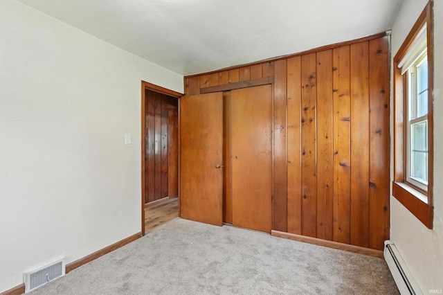 58 W Markle Rd, Huntington, IN 46750 - unfurnished bedroom with baseboard heating, carpet floors, a closet, and wooden walls