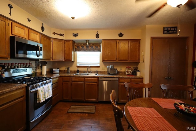 3718 George Washington Rd, Lafayette, IN 47909 - kitchen featuring stainless steel appliances, brown cabinets, a textured ceiling, dark wood finished floors, and dark countertops