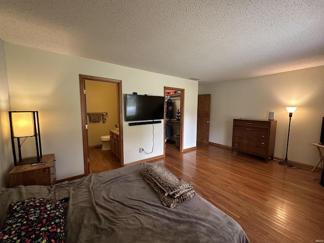 1701 Fairway Dr, Kokomo, IN 46901 - bedroom featuring wood finished floors, a textured ceiling, a walk in closet, ensuite bath, and a closet