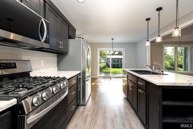 16807 Darling Rd, Woodburn, IN 46797 - kitchen featuring stainless steel appliances, light wood finished floors, a kitchen island with sink, pendant lighting, and light stone countertops