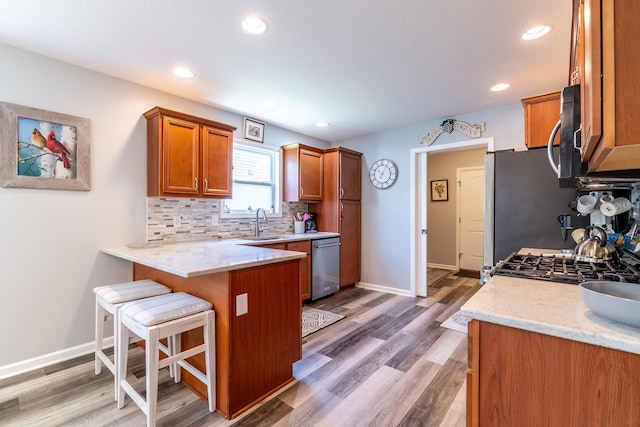 1709 Krebs Ct, Angola, IN 46703 - kitchen featuring appliances with stainless steel finishes, brown cabinetry, backsplash, a kitchen breakfast bar, and a peninsula