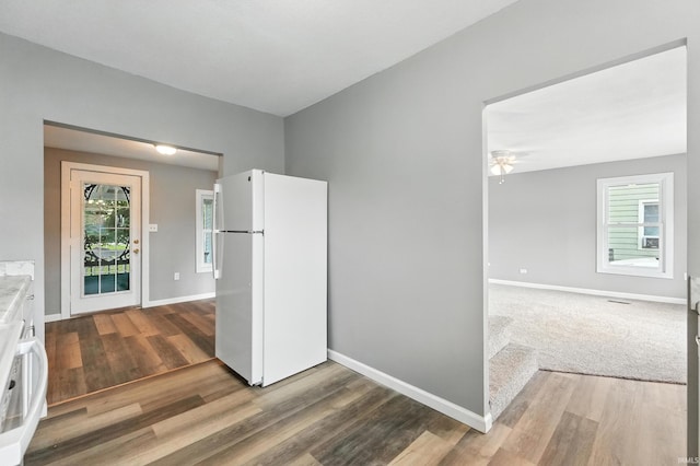 615 E Main St, Butler, IN 46721 - kitchen with freestanding refrigerator, wood finished floors, ceiling fan, stove, and white cabinets