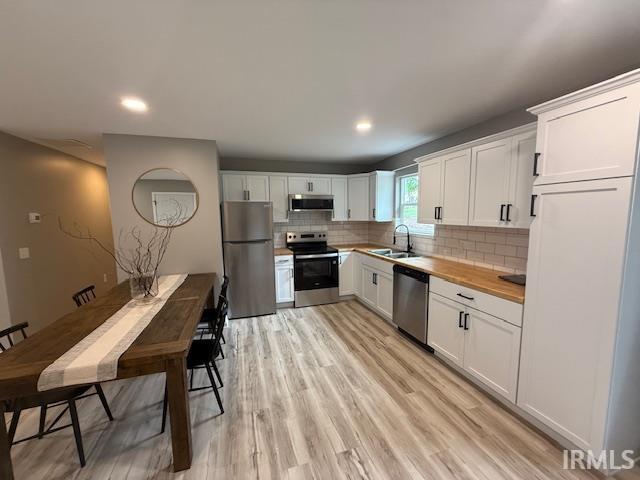 3419 Logan Ave, Fort Wayne, IN 46803 - kitchen featuring appliances with stainless steel finishes, decorative backsplash, white cabinetry, light wood finished floors, and recessed lighting