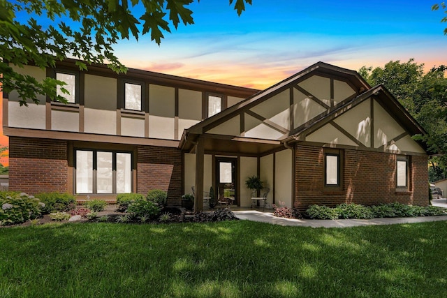 6521 Woodthrush Dr, Fort Wayne, IN 46835 - back of property at dusk with brick siding, a lawn, and stucco siding