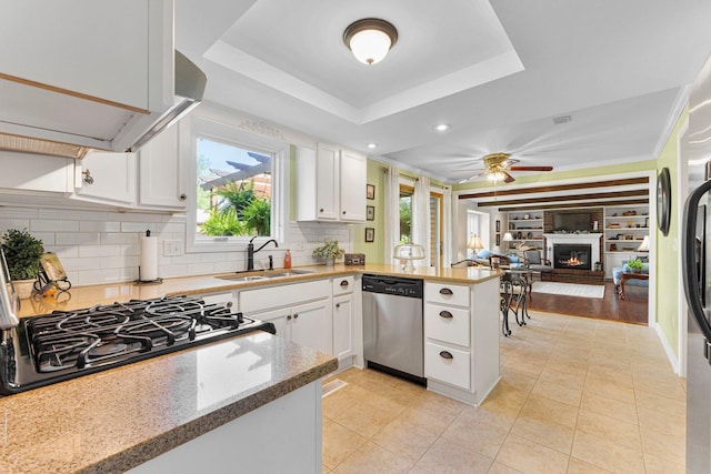 6521 Woodthrush Dr, Fort Wayne, IN 46835 - kitchen featuring stainless steel dishwasher, a peninsula, a glass covered fireplace, white cabinets, and recessed lighting