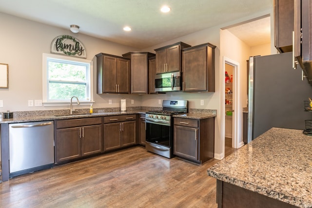 3951 W Nimita Ct, Bloomington, IN 47404 - kitchen featuring stainless steel appliances, light wood-type flooring, recessed lighting, dark brown cabinetry, and light stone countertops