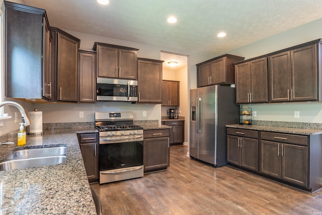 3951 W Nimita Ct, Bloomington, IN 47404 - kitchen with appliances with stainless steel finishes, wood finished floors, dark brown cabinets, light stone counters, and recessed lighting